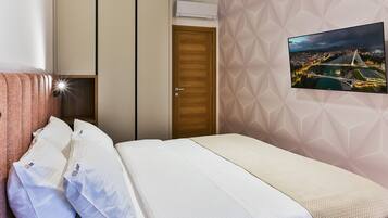 Habitación de hotel con cama, almohadas, armario, equipo de aire acondicionado y vista panorámica de la ciudad en la pared.
