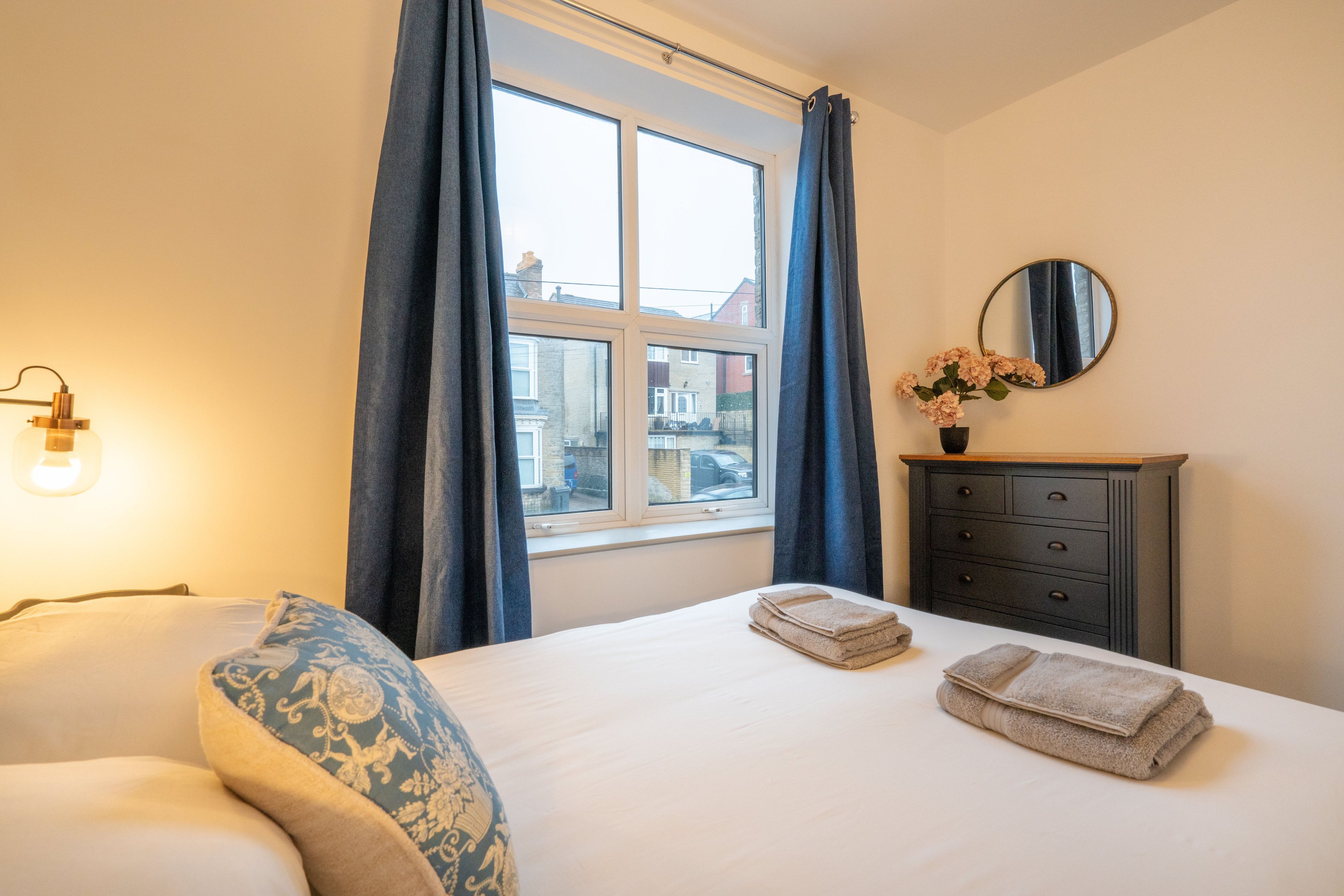 Een hotelkamer met een bed, een dressoir, een spiegel en een raam met gordijnen.