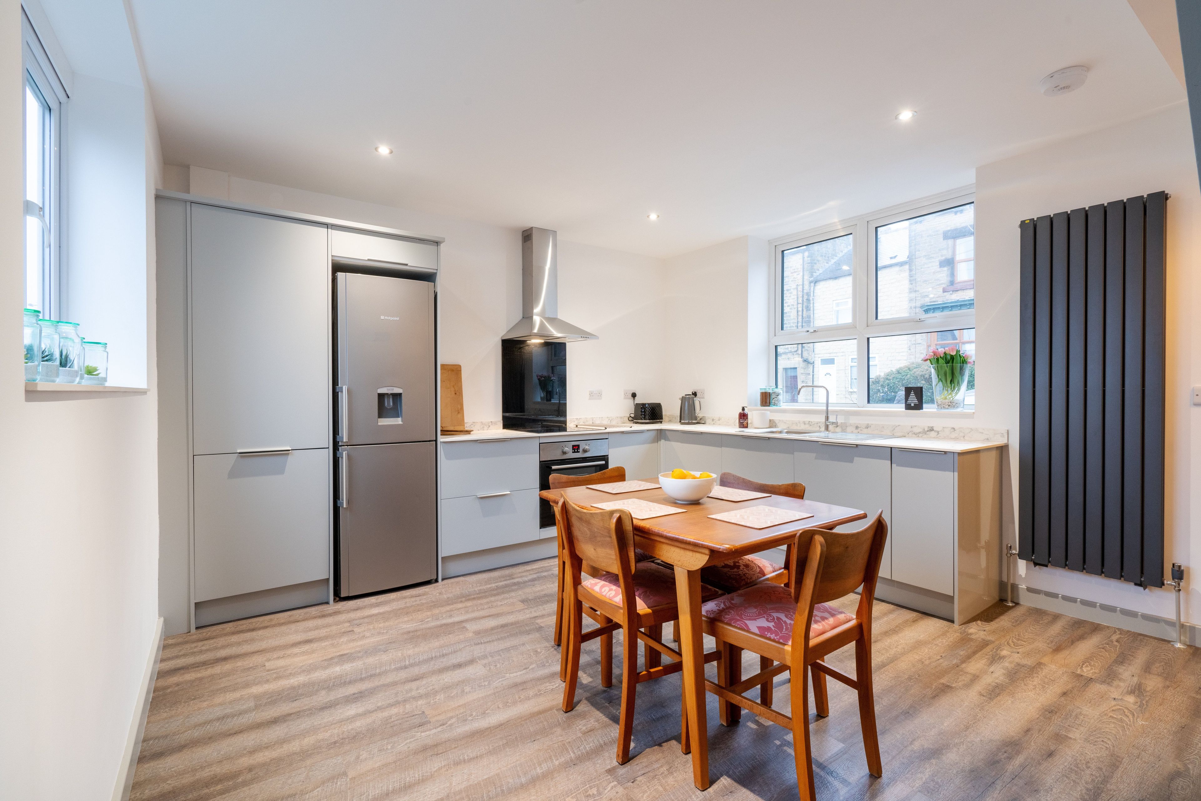A modern kitchen with a built-in oven, a stainless steel refrigerator, and a window overlooking the street.