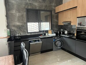 Cozinha moderna equipada com lava-louças embutida, máquina de lavar e fogão.