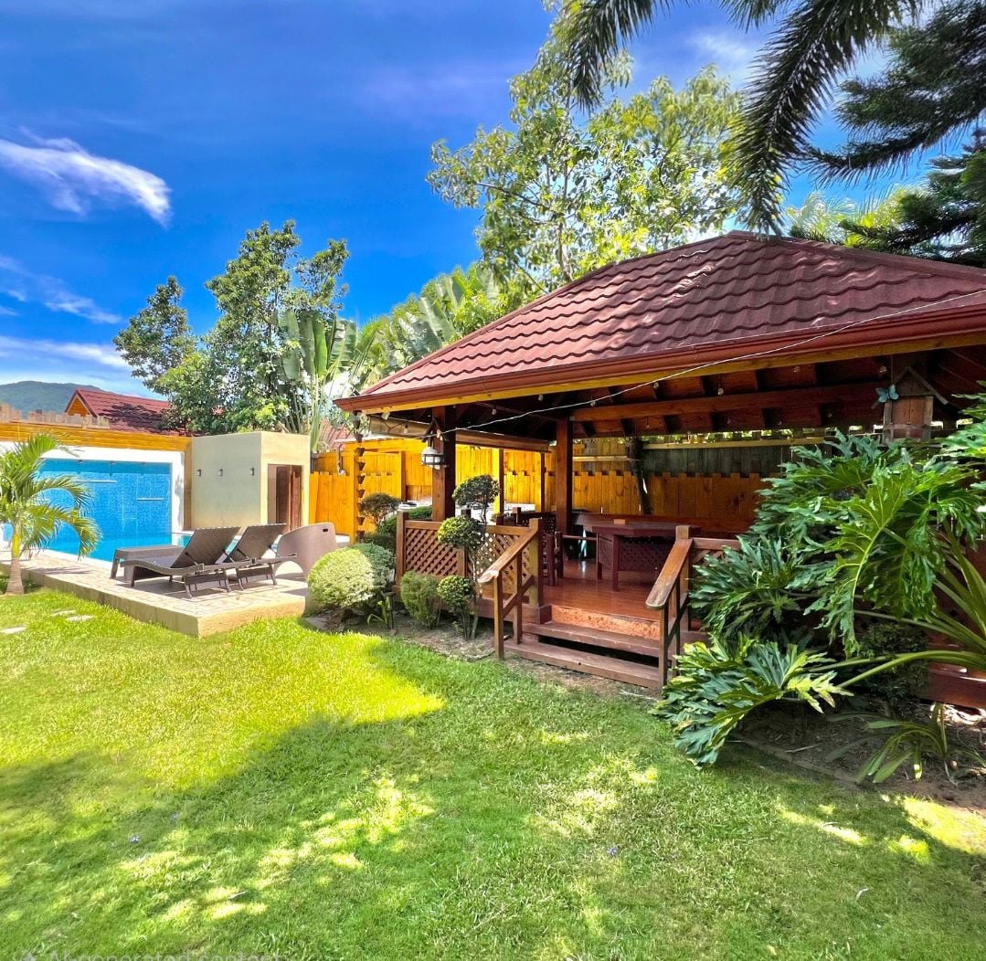 Uma casa com piscina, alpendre coberto e um jardim bem cuidado.