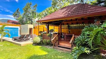 Uma casa com piscina, alpendre coberto e um jardim bem cuidado.