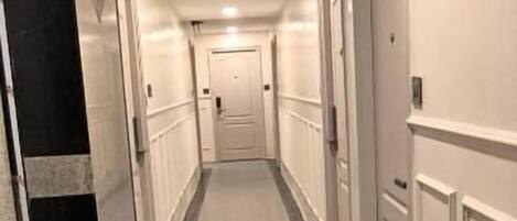 A hotel corridor with doors on both sides, a marble floor, and a light ceiling.