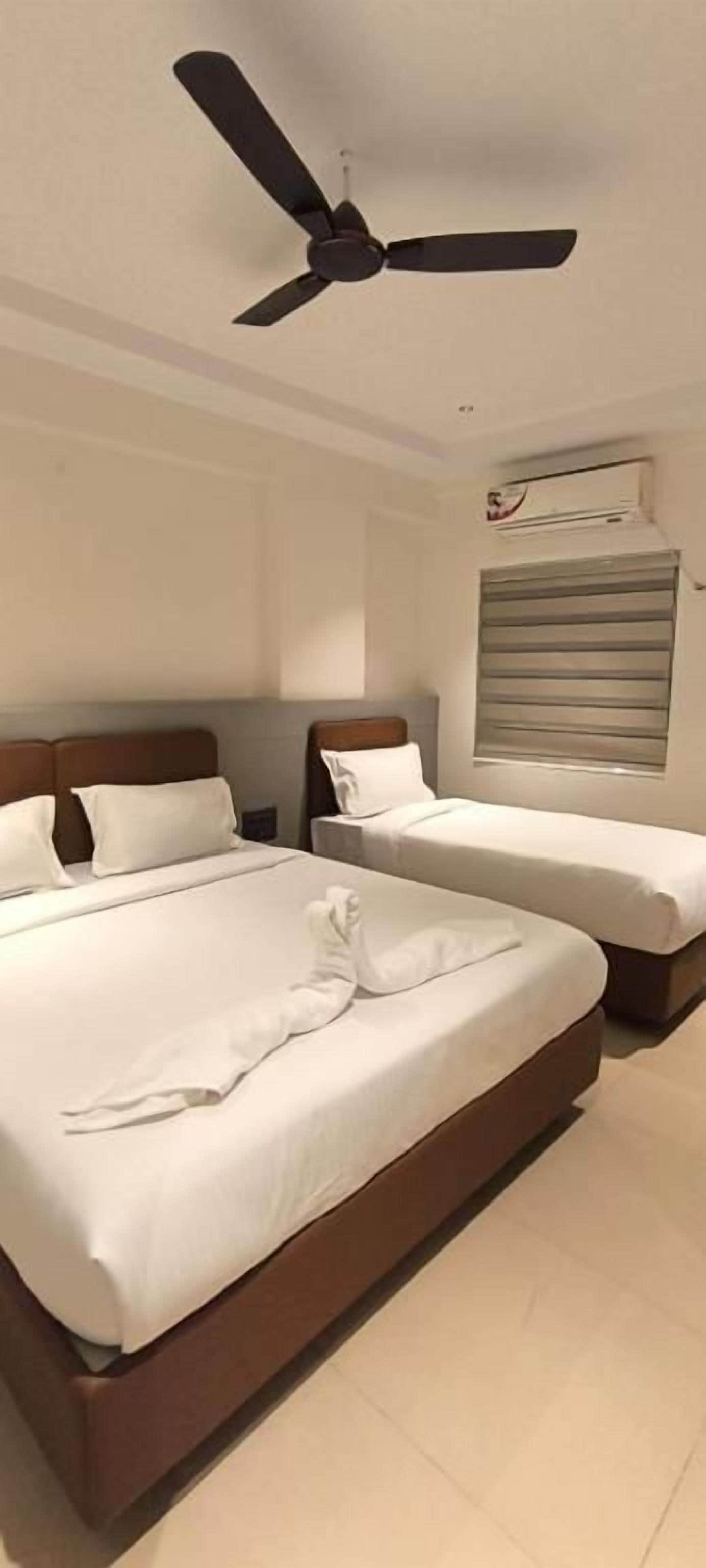 Ein Hotelzimmer mit zwei Betten, einem Deckenventilator und einer Klimaanlage.