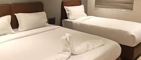 A hotel room with two beds, a ceiling fan, and an air conditioning unit.