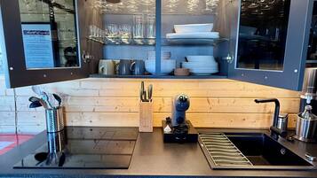 Une cuisine moderne équipée d’un meuble à vin intégré, d’une machine à café et d’un évier.