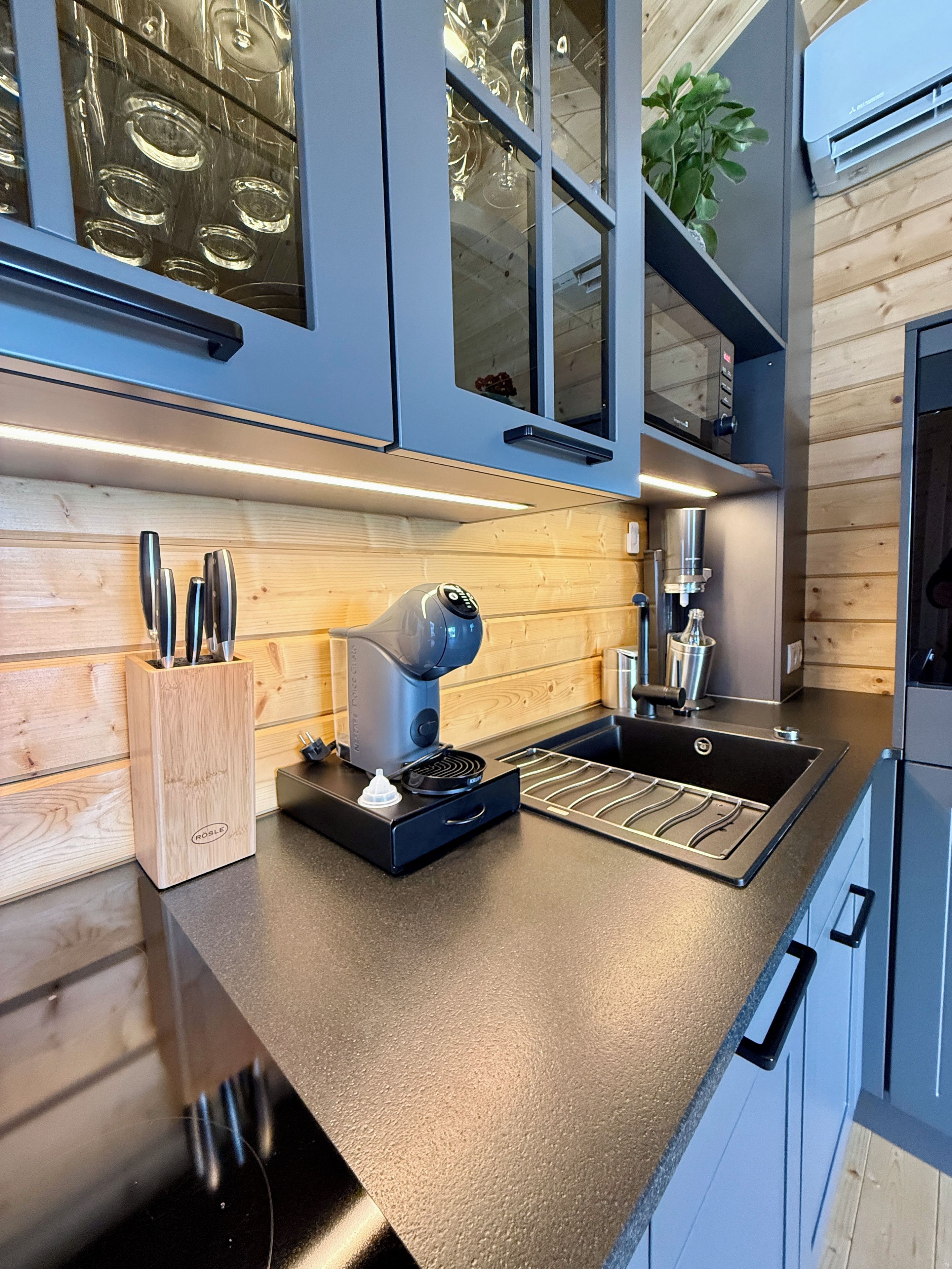 Eine moderne Küche mit Kaffeemaschine, Spüle und Holzschränken.