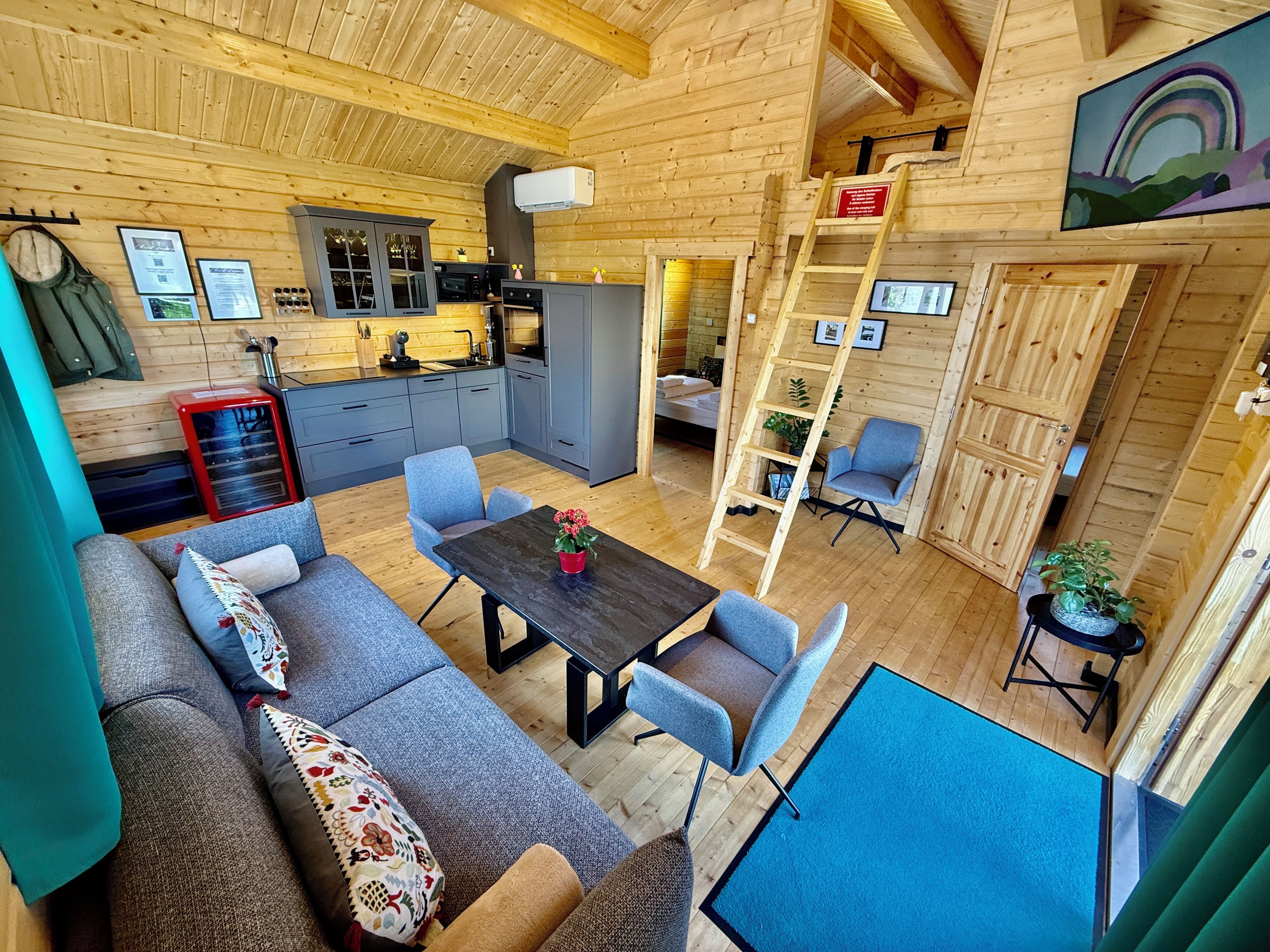 Een modern ingerichte blokhut met een eethoek, keuken en een slaaploft.