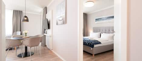 Una habitación de hotel moderna con una cama, un escritorio con sillas, un televisor y obras de arte en las paredes.
