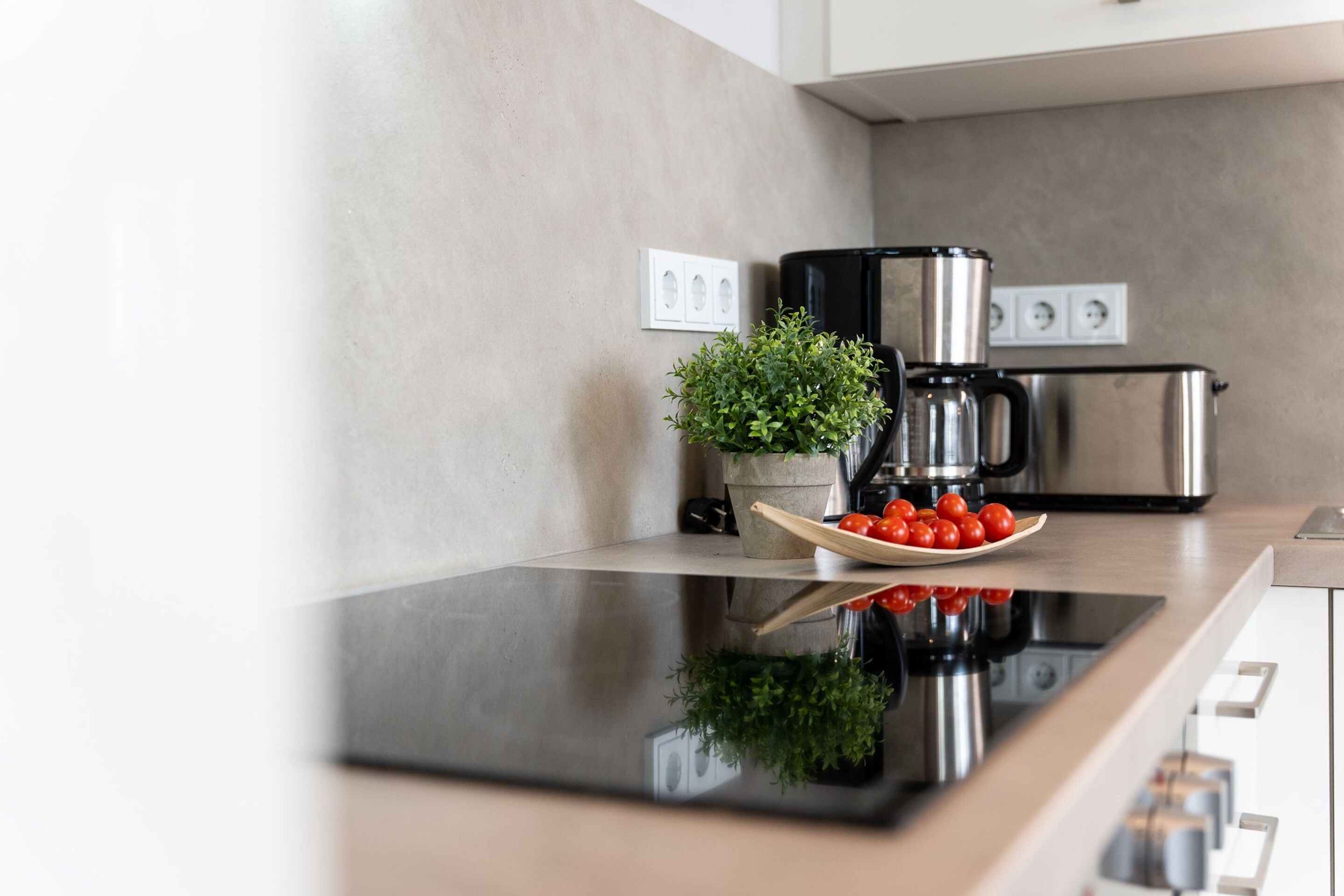 Una cocina moderna con tope de cocción por inducción negro, electrodomésticos de acero inoxidable y una planta en la encimera.