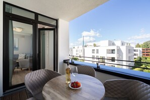 A balcony with a table, chairs, a bottle of wine, and a plate of fruit. - Modern Holiday Apartment With Sunny Loggia (Lübeck)