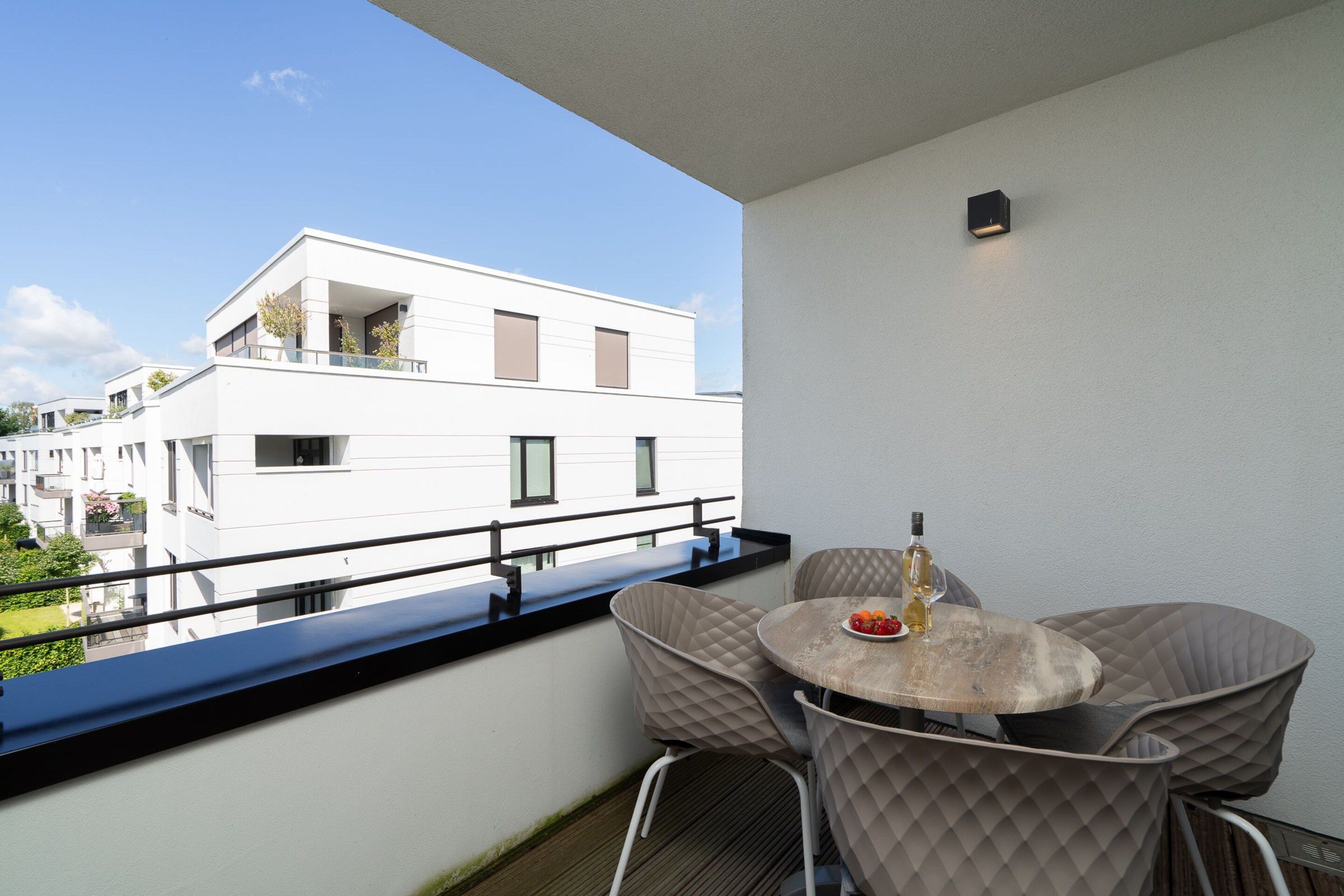 Un balcón con mesa y sillas, con vista a un edificio moderno.