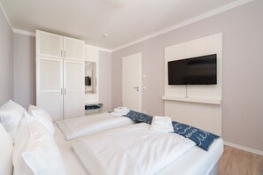 Habitación de hotel con dos camas, un armario, televisor y baño.