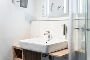 Et stilfuldt badeværelse med en hvid vask, kromarmatur og et trækommode.