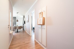 A hallway with wooden flooring, a dining area with chairs and a table, and a wall-mounted towel rack. - Modern Holiday Apartment With Sunny Loggia (Lübeck)