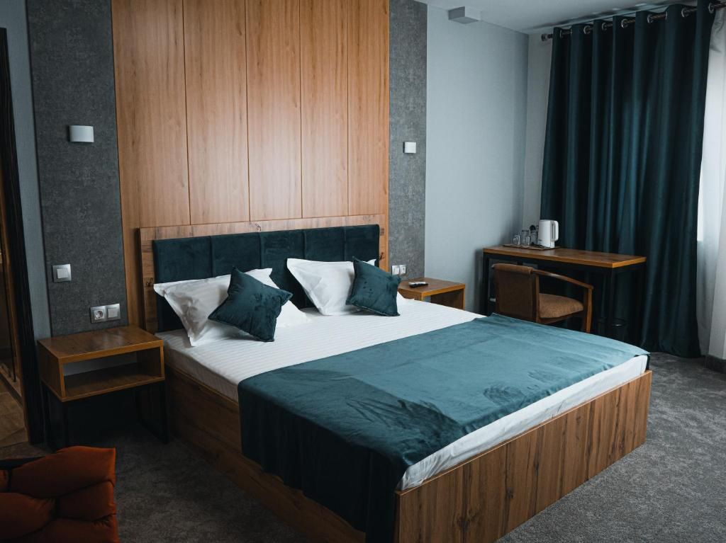 A modern hotel room with a large bed, wooden headboard, and a nightstand with a lamp.