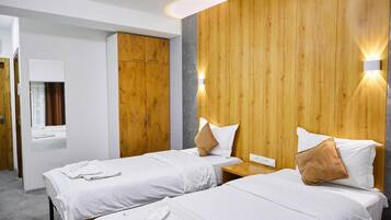A hotel room with two beds, wooden paneling on the walls, and a mirror above the left bed.