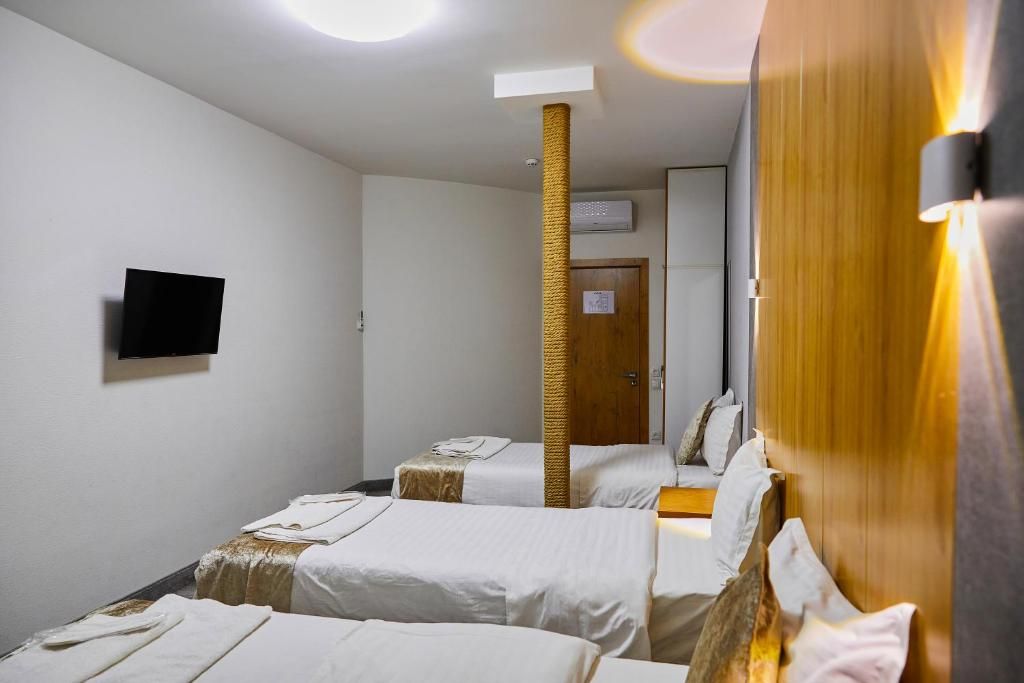 Habitació d'hotel amb dos llits, un televisor de pantalla plana fixat a la paret, un pilar de fusta i una porta amb un cartell.