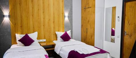 A hotel room with two beds, wooden paneling on the wall, a nightstand, and a mirror.