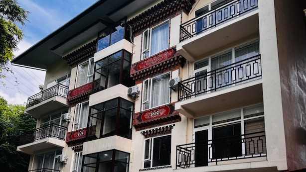 Een meerhoog gebouw met balkons, airconditioning en een traditionele decoratieve gevel.
