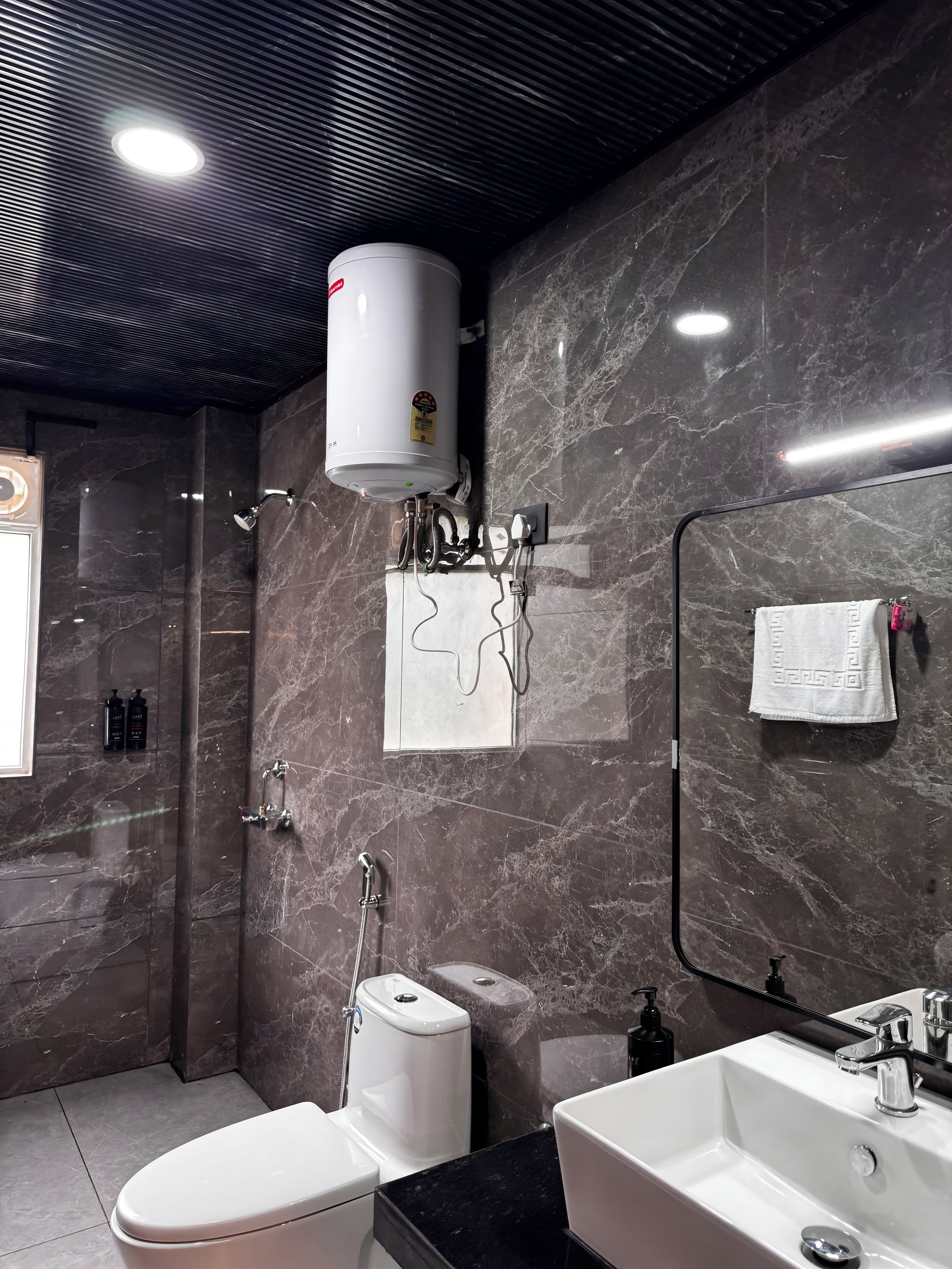 Un baño moderno con ducha integrada, inodoro, lavabo y toallero.
