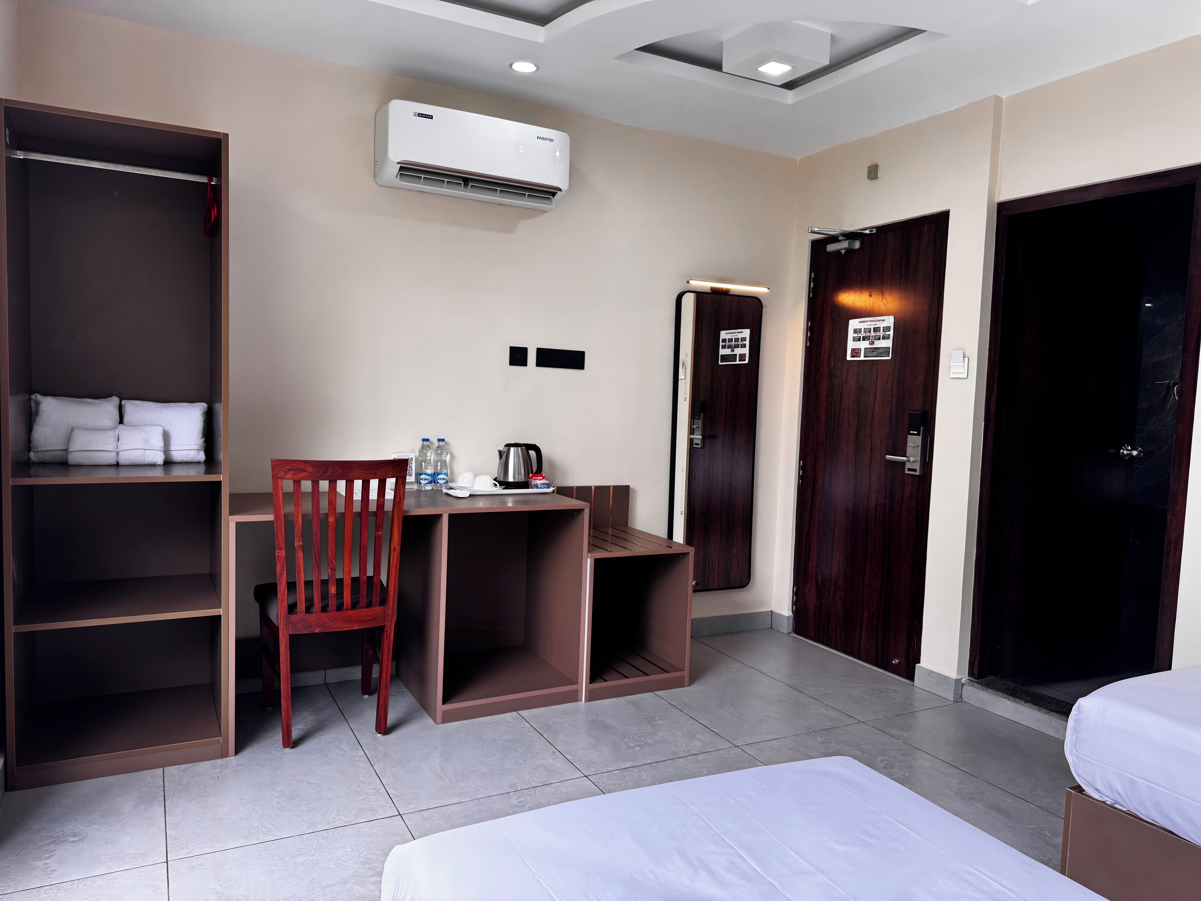 Een hotelkamer met een bed, een bureau, een stoel, een kledingkast en een airconditioning.