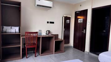 Een hotelkamer met een bed, een bureau, een stoel, een kledingkast en een airconditioning.