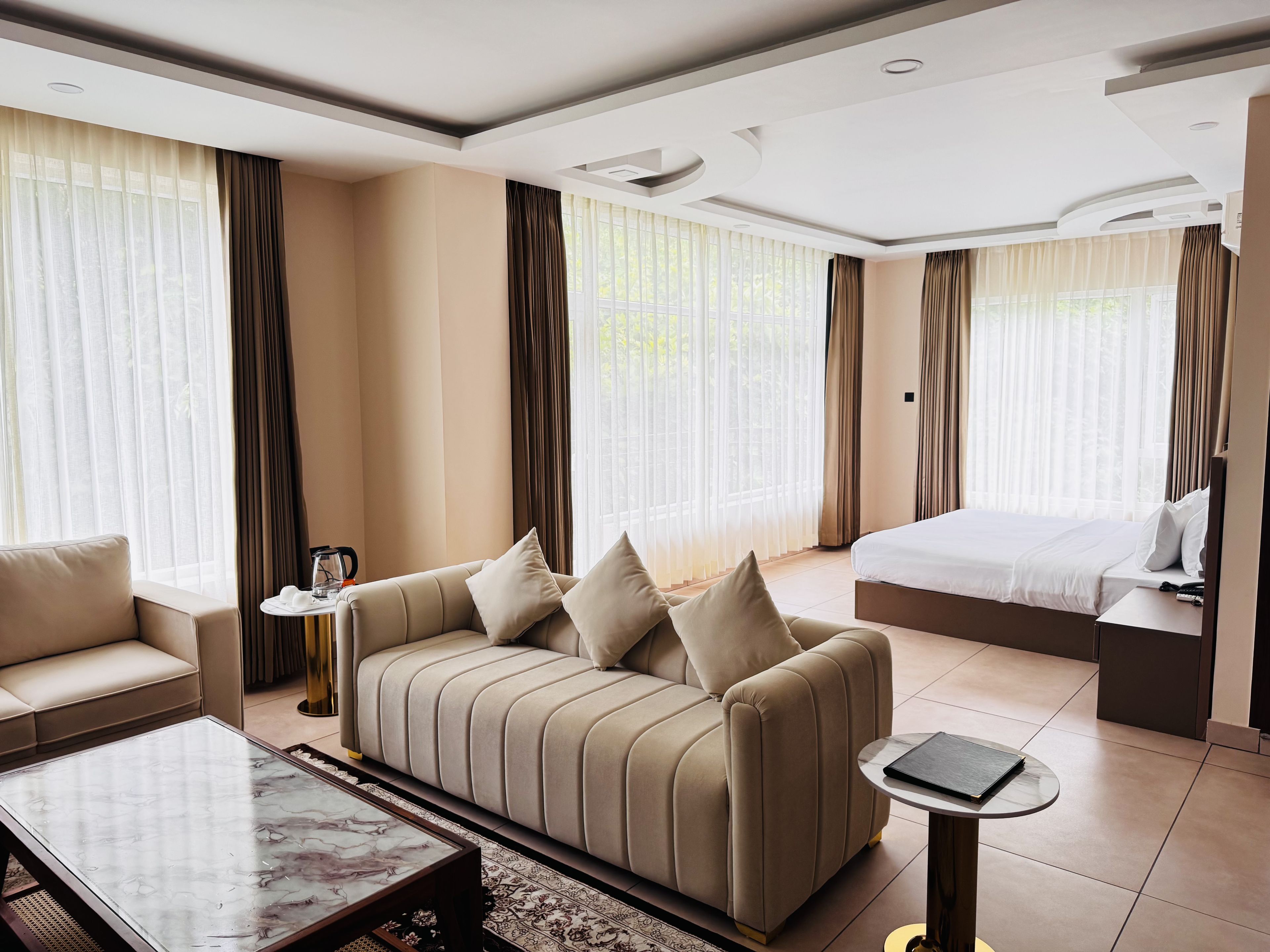 Een hotelkamer met een bank, een bed, een bijzettafeltje en een klein nachtkastje.