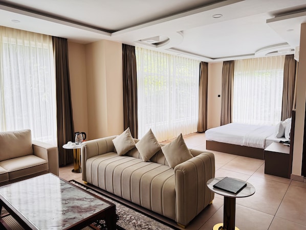 A hotel room with a sofa, a bed, a coffee table, and a small side table.