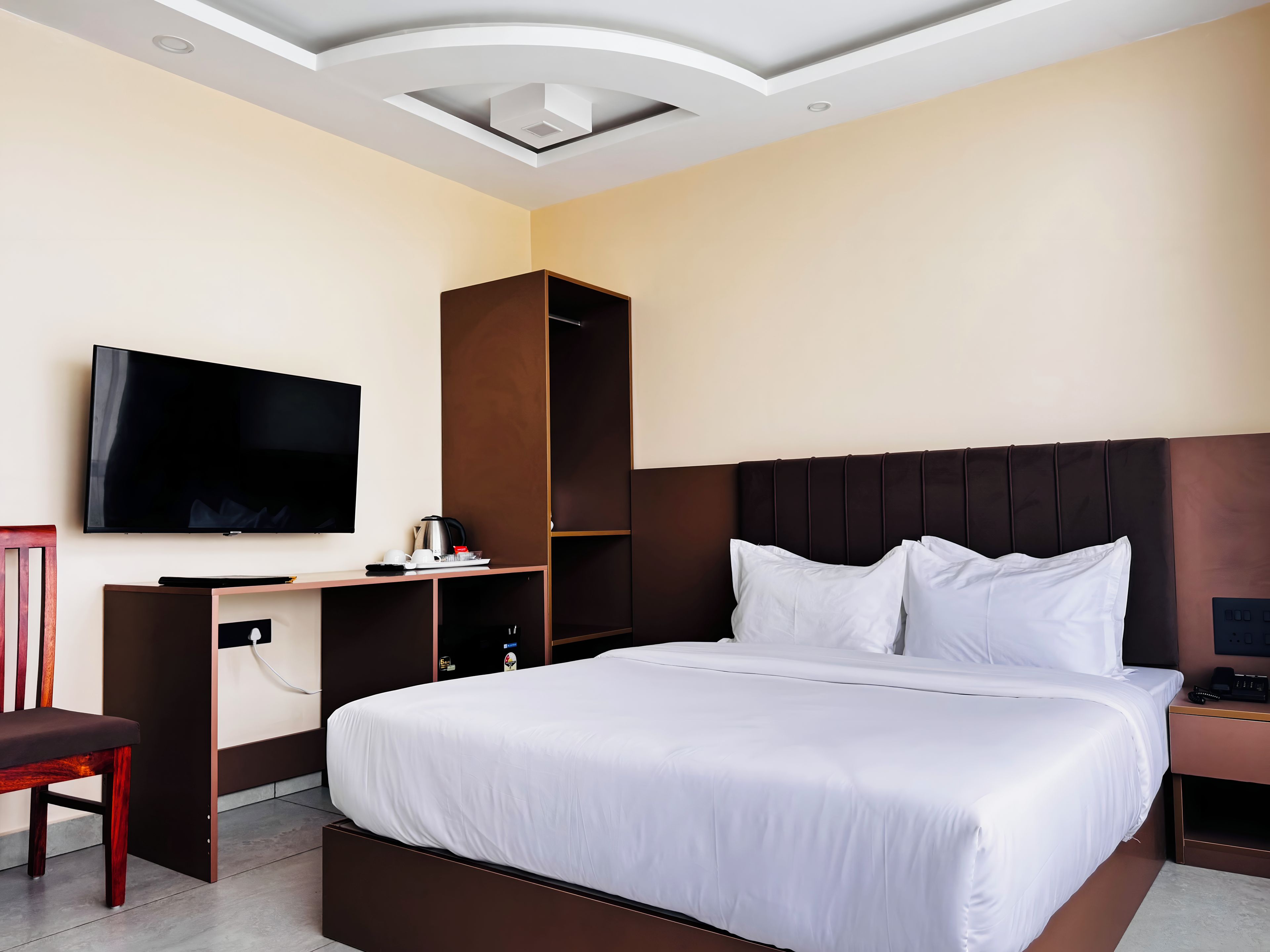 A hotel room with a bed, a TV, a desk, and a wardrobe.