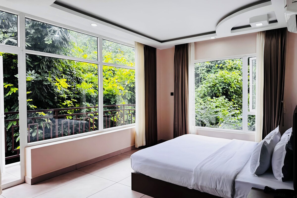 A modern bedroom with a large window, a bed, and a nightstand.