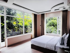 A modern bedroom with a large window, a bed, and a nightstand. - GawaiLing Residency (Samtse)
