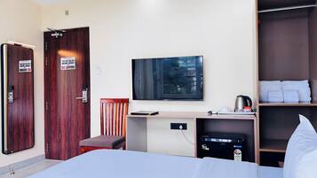 Habitación de hotel con cama, escritorio, silla, armario y televisor de pantalla plana.