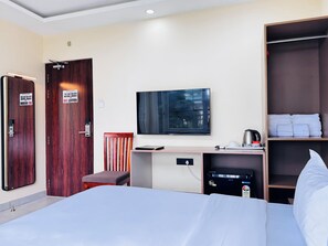 Habitación de hotel con cama, escritorio, silla, armario y televisor de pantalla plana.