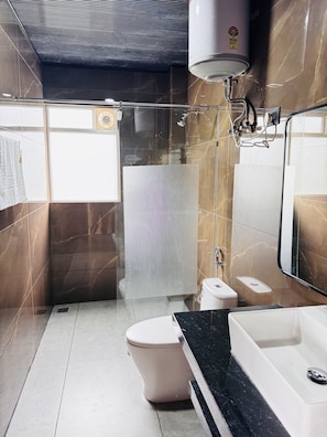 A modern bathroom with a glass shower enclosure, a toilet, a sink, and a bathtub. - GawaiLing Residency (Samtse)
