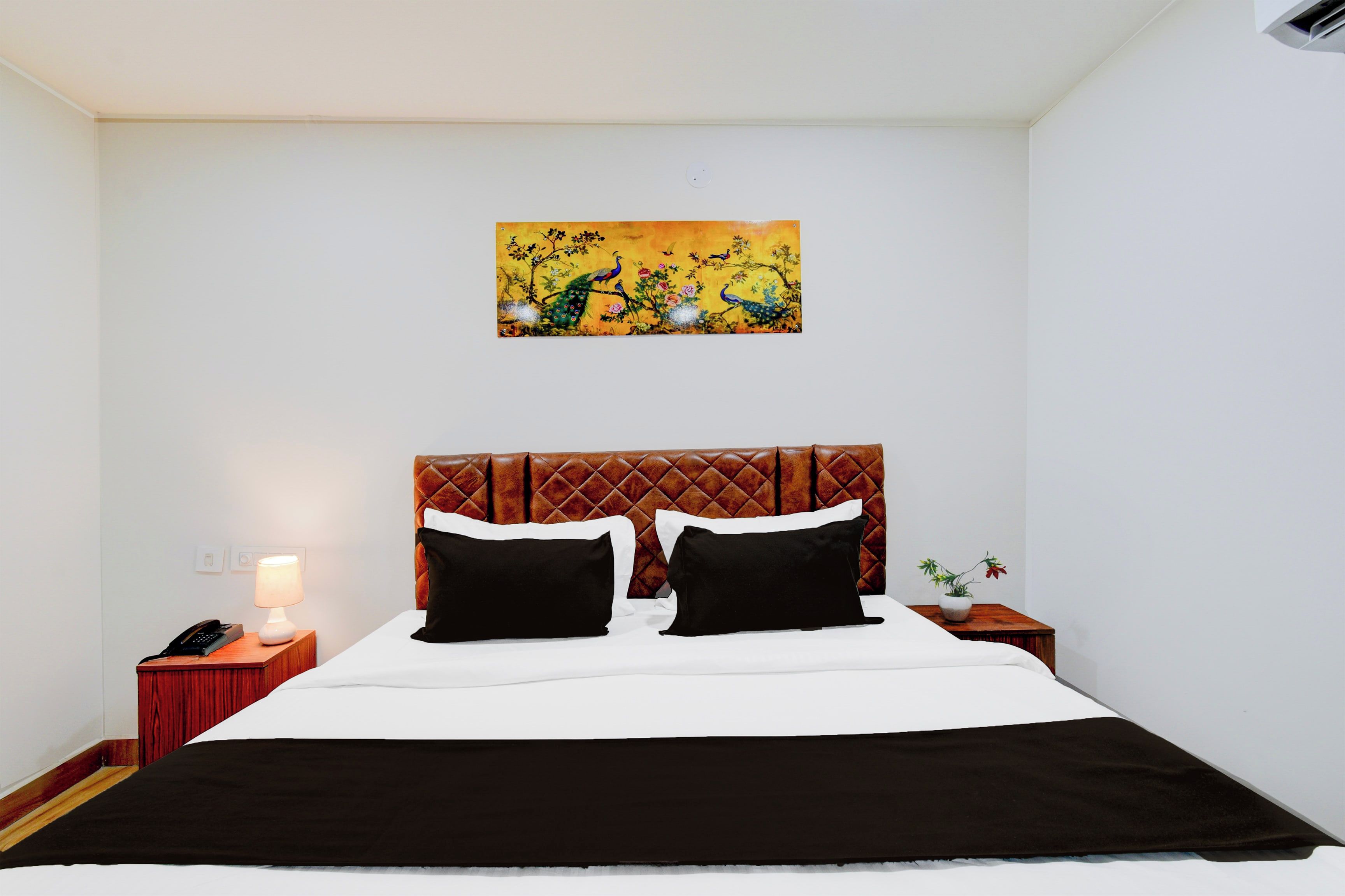 Una habitación de hotel con una cama, una mesita de noche, una lámpara y un cuadro en la pared.