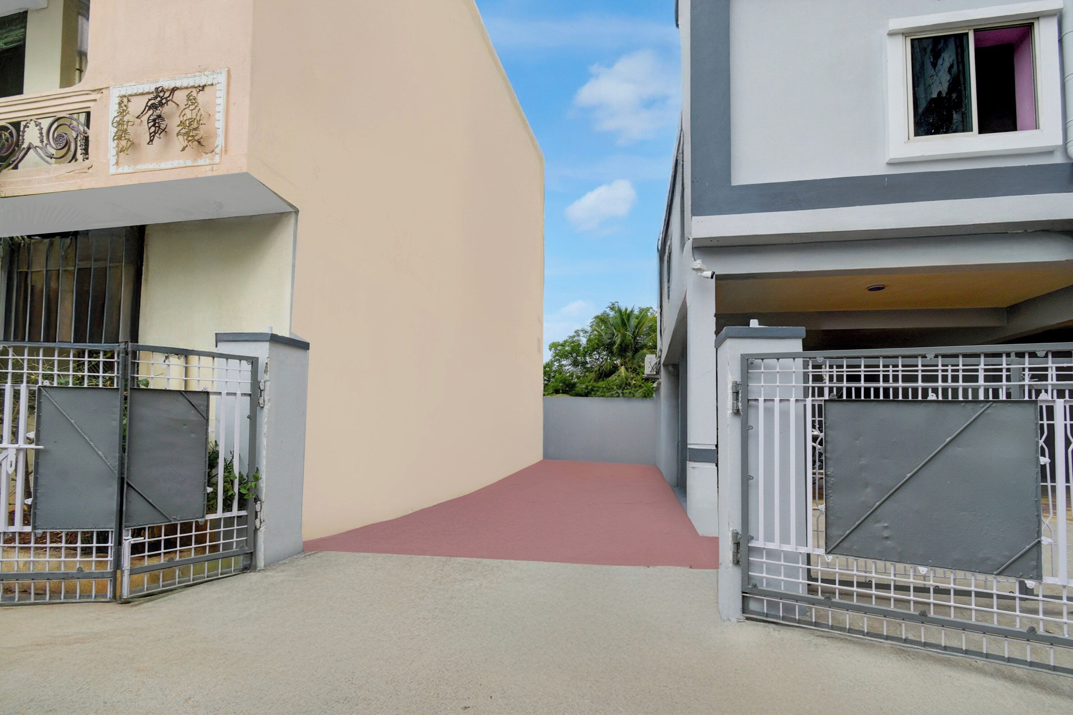 Ein verschlossenes Einfahrtstor zu einem Wohngebiet, wobei ein Betonweg zu einem Gebäude führt.