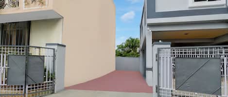 A gated entrance to a residential area with a concrete pathway leading to a building.