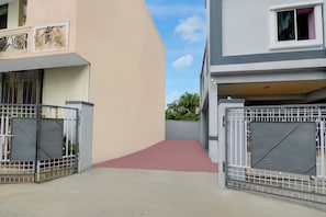 Una entrada con reja a una zona residencial, con un camino de hormigón que conduce a un edificio.