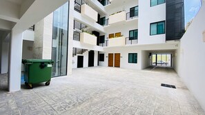 A multi-level building with a courtyard, balconies, and a green trash bin. - Beachfront Views next to the pier (Puerto Morelos)