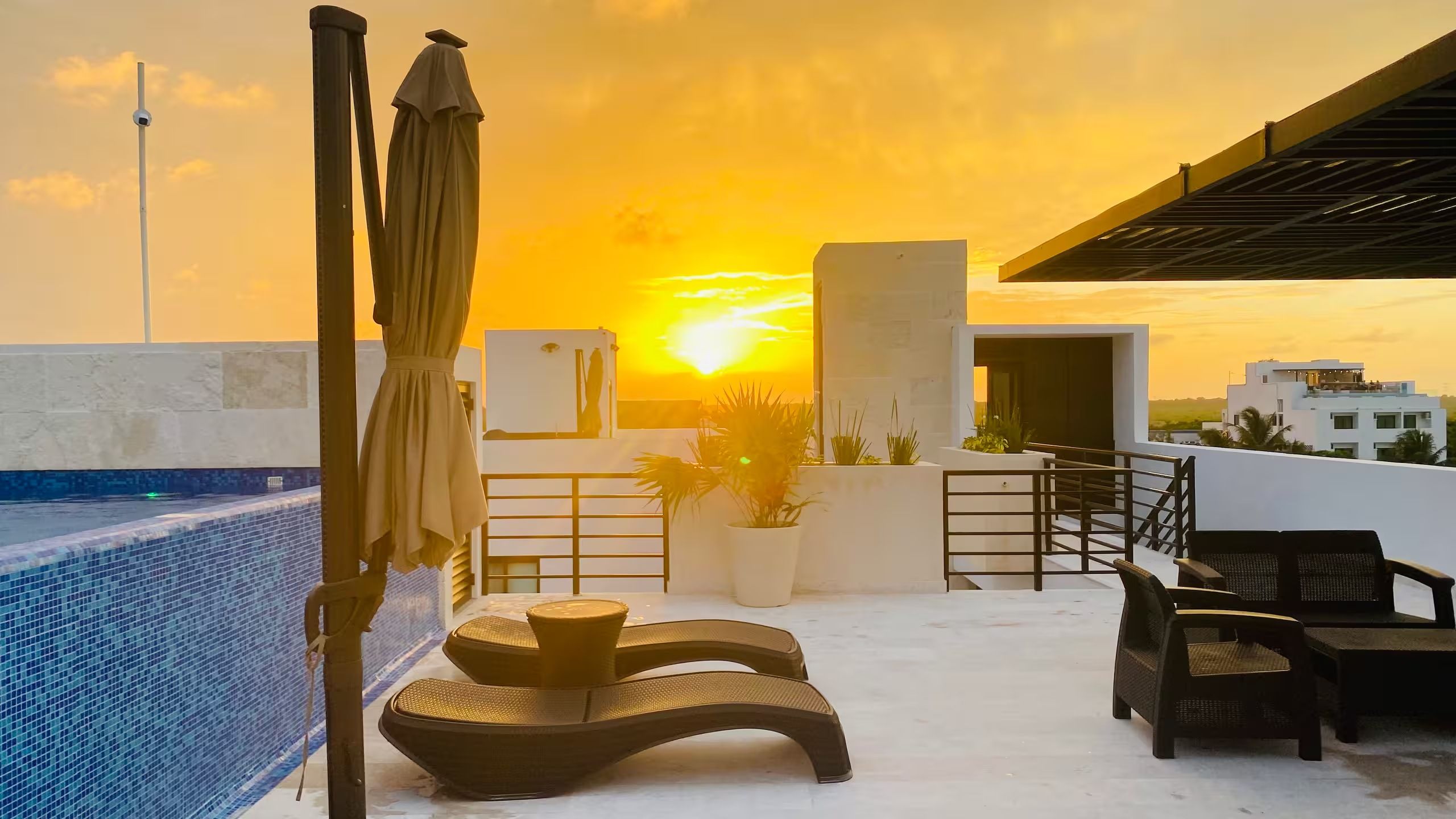 Eine Dachterrasse mit Pool, Liegestühlen und Blick auf den Sonnenuntergang.