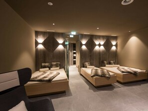 A modern spa room with three beds, each with a fur throw, and a massage chair. - Apartment in Schruns With Swimming Pool (Schruns)