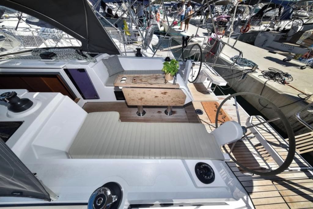 A boat deck with a seating area, a small table, and a potted plant.