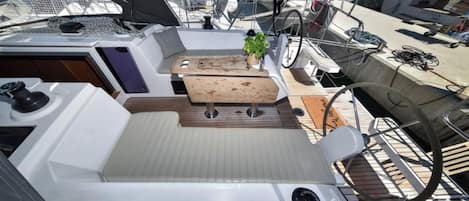 A boat deck with a seating area, a small table, and a potted plant.