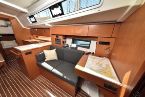 Een compact, goed verlicht interieur met een bank, een tafeltje, een kaart en een bedieningspaneel.