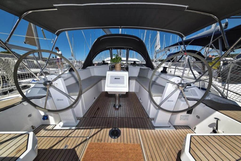 A boat deck with a steering wheel, a control panel, and a covered area.