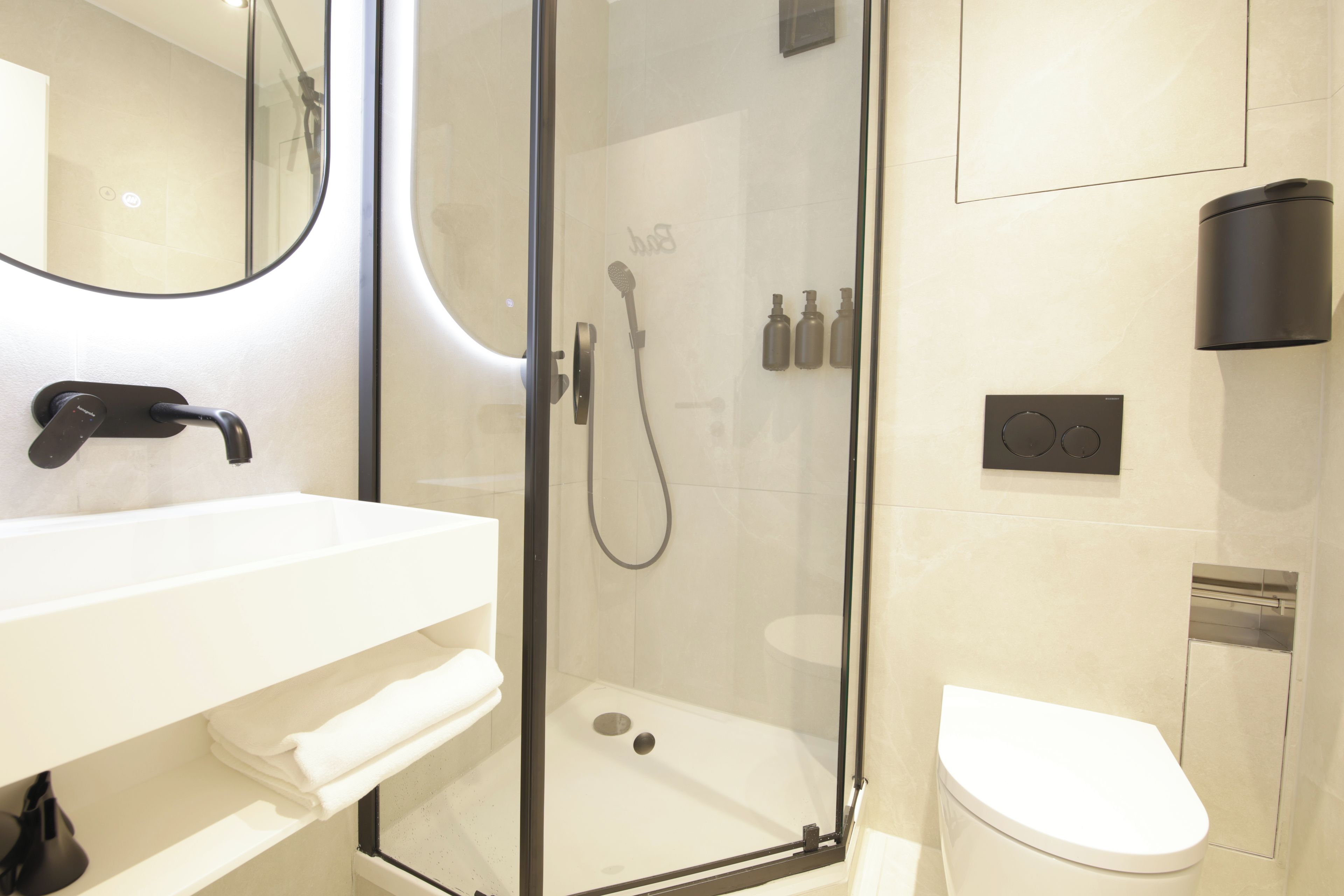 Ein modernes Badezimmer mit einer Duschkabine aus Glas, einem weißen Waschbecken und einer Toilette.
