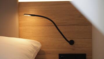 A wooden headboard with a modern bedside lamp and a power outlet.