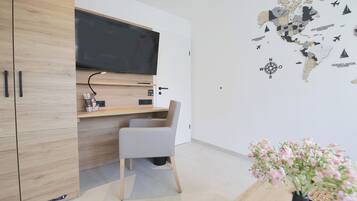 A modern room with a wooden wardrobe, a desk with a flat-screen TV, a chair, and a wall map.