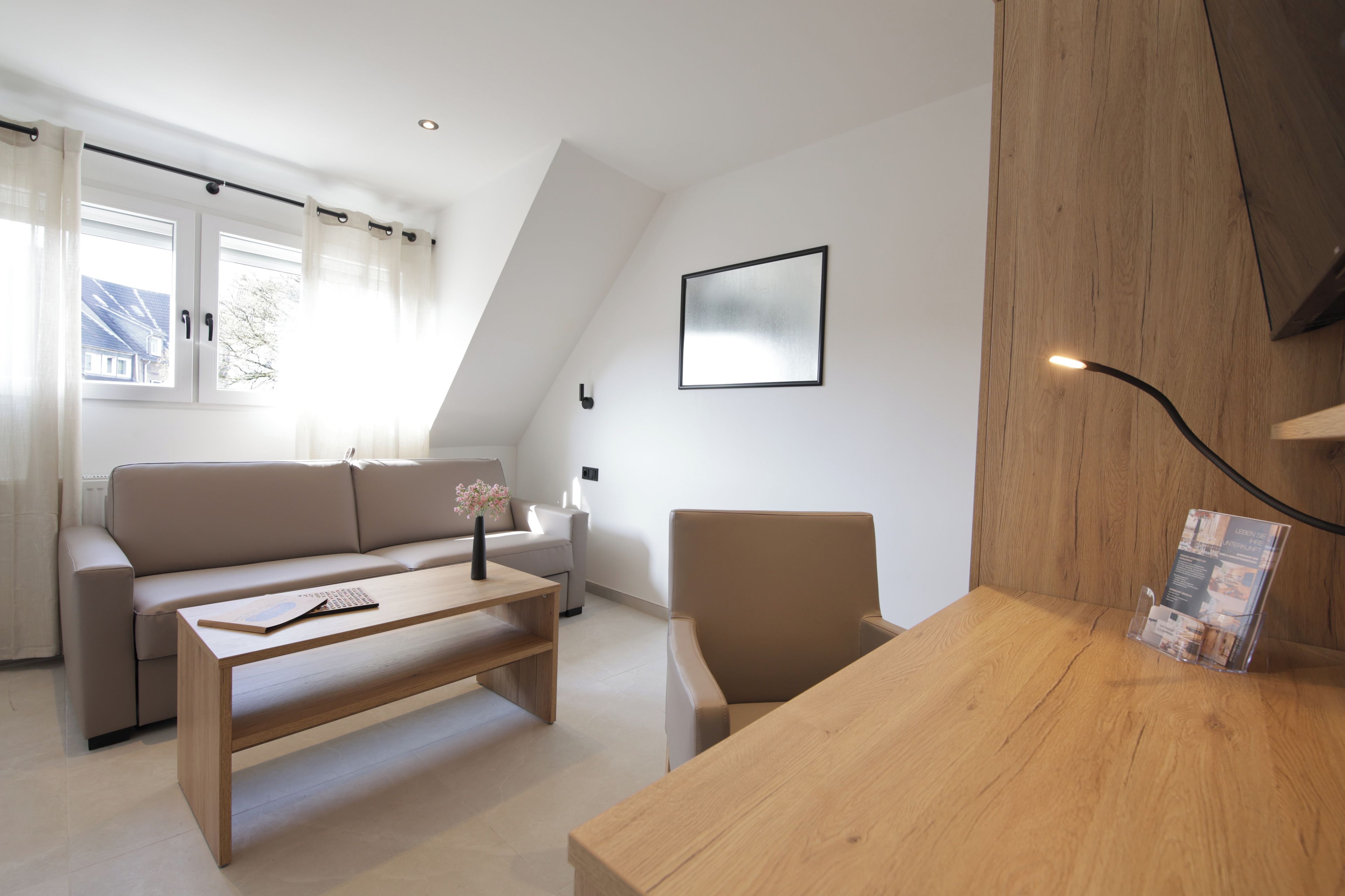 A modern living room with a sofa, a coffee table, a chair, and a wooden desk.